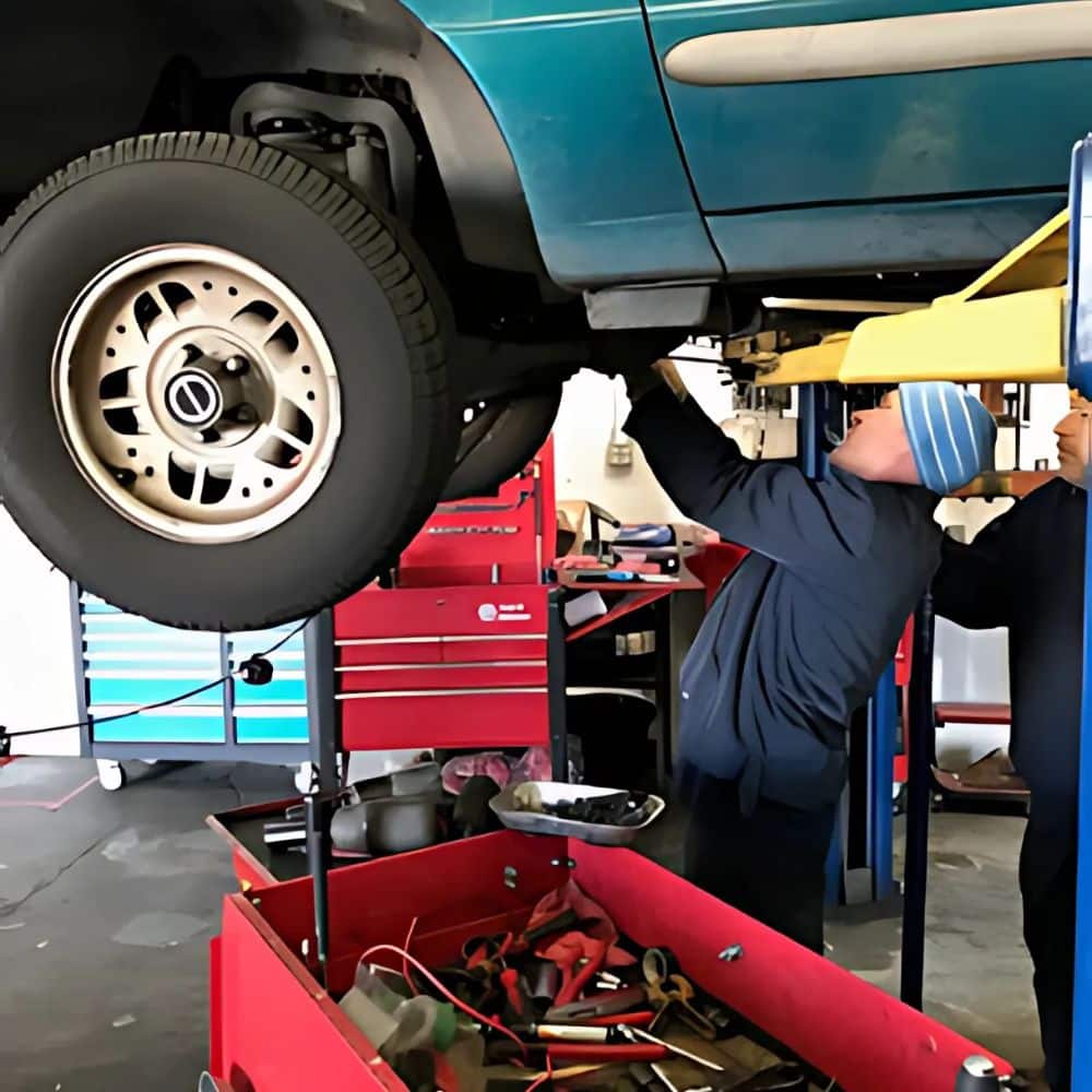 Poway auto repair experts at work beneath a car on a lift.